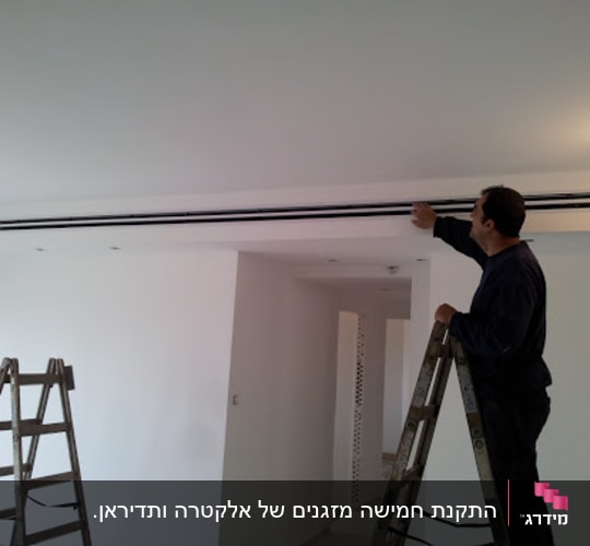 אדם על סולם מתקין מזגן בתקרה